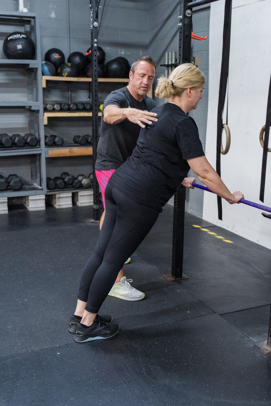 RNF coach giving hands-on feedback while a client stretches with a bar