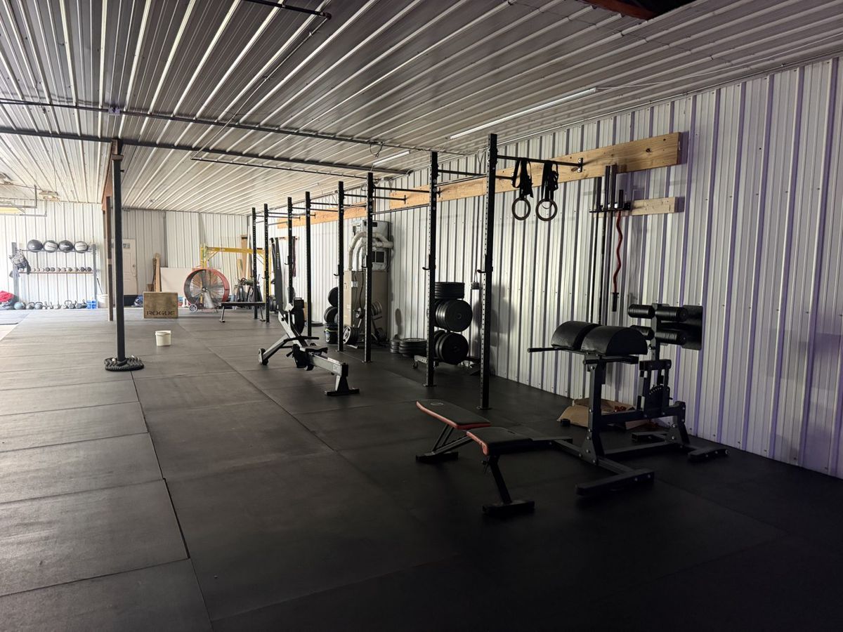 The RNF CrossFit 24/7 open-gym area with mats, benches, rigs, dumbbells, and barbells